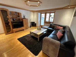 a living room with a black leather couch and a table at Apartment Bergfreude in Saas-Grund