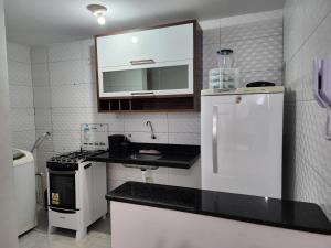 a kitchen with a white refrigerator and a sink at Apartamento para suas férias ou trabalho in João Pessoa