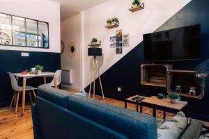 a living room with a blue couch and a tv at Evasion romantique & spa in Saint-Étienne +9 photos