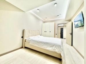a white bedroom with a bed and a tv at Замечательная новая квартира на Ботанике in Chişinău