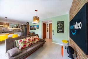 a living room with a couch and a kitchen at Ykutiba H04 - com jardim in Imbassai