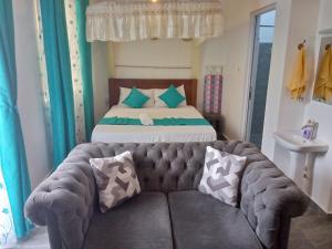 a bedroom with a bed and a couch with pillows at Pride Studio II in Mombasa