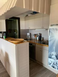 une cuisine avec des armoires blanches et un comptoir dans l'établissement Campanules, à Courchevel