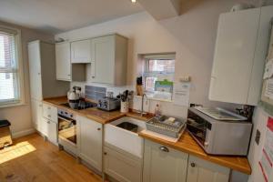 a kitchen with white cabinets and a wooden counter top at The Little Angel Cottage in Whitby