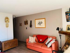 - un salon avec un canapé orange et des oreillers dans l'établissement Campanules, à Courchevel 1 autre photo