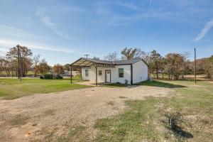 un pequeño edificio blanco en un campo con patio en Lake Fork Cabin with Boat Launch and Fishing Pier, en Quitman