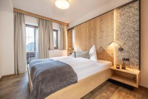 a bedroom with a large bed with a wooden wall at Appartements Liftstüberl in Alpbach