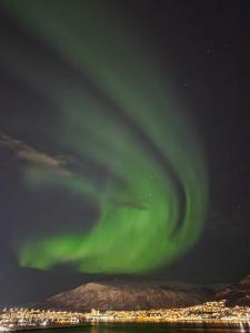 an aurora borealis in the sky over a city at Seaside city appartment in Tromsø