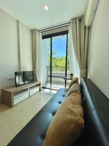 Una sala de estar con un sofá y una ventana grande. en 1 bedroom pool view in Bangtao, en Thalang