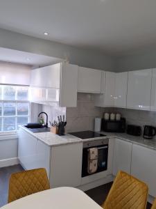 eine Küche mit weißen Schränken und einem Herd mit Backofen in der Unterkunft Casa De Niveles Near Beach Local Comfort in Weymouth