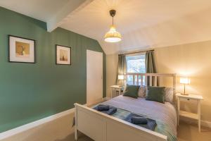 Un dormitorio con una cama y una pared verde. en Charming 5-Bed Home with Garden and Parking, en Winchester