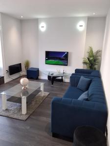 ein Wohnzimmer mit einem blauen Sofa und einem Fernseher in der Unterkunft Casa De Niveles Near Beach Local Comfort in Weymouth