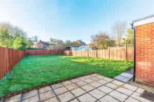 un patio trasero con una valla y césped verde en Charming 5-Bed Home with Garden and Parking, en Winchester
