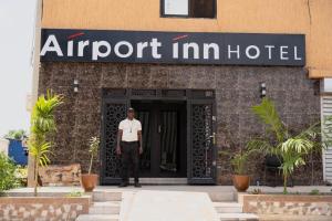 a man standing in front of an airport inn hotel at Airport INN Hotel in Lomé