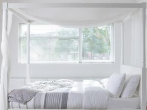 a white bedroom with a bed and a window at Cosy Garden Flat, Private Hot Tub & Four Poster Bed in York