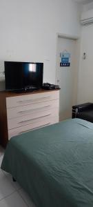 a bedroom with a bed and a tv on a dresser at Suíte na Cobertura Enseada in Guarujá