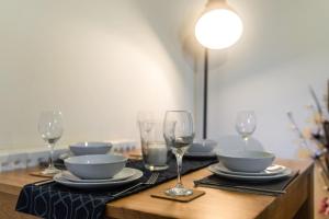una mesa con platos, tazones y copas de vino en 12FWC, 2 Bedroom Apartment, Sleeps 4, Free Parking, Town Centre Location, en Swindon