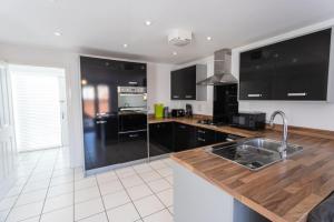 ブリストルにあるOverdrive rd - Long Stay Contractors by ShortStayUKのキッチン(黒いキャビネット、木製カウンタートップ付)