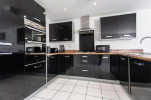 ブリストルにあるOverdrive rd - Long Stay Contractors by ShortStayUKのキッチン(黒いキャビネット、ステンレス製の電化製品付)