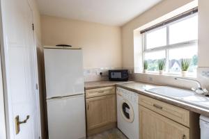 a kitchen with a white refrigerator and a sink at Thorley Apartment in North Swindon, Sleeps 4 in 2 bedrooms, Long Stay Disc, Parking in Swindon +9 photos
