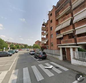 an empty street with cars parked in a parking lot at Casa del Viandante in Nichelino