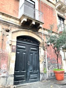 una grande porta nera su un edificio con balcone di Siculahome23 a Catania