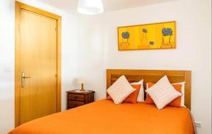 a bedroom with a bed with an orange bedspread at 9Arches in Vila Nova de Poiares