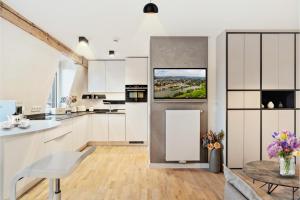 a kitchen with white cabinets and a tv on the wall at Modern Elegance in historical City Center in Trier