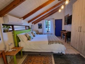 a bedroom with a large bed and a desk at The Sculpture Yard in Gordonʼs Bay