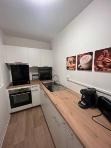 una cucina con mobili bianchi e un piano di lavoro di Cœur de ville a Lens Altre 14 foto