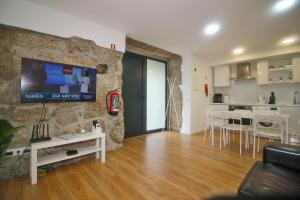 ein Wohnzimmer mit einem Fernseher an einer Steinwand in der Unterkunft Casa da Foz by Gerês Casas in Ventosa