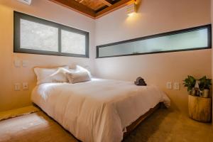 a bedroom with a large white bed with two windows at Bright 2BR Loft with Rooftop Pool in Best Tulum Downtown Location in Tulum +43 photos