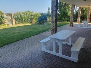 einen Picknicktisch und zwei Bänke auf einer Backsteinterrasse in der Unterkunft 36 Steps to Beach Sand in Gqeberha