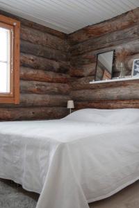 a bedroom with a white bed and wooden walls at Vuokatinportintie in Vuokatti