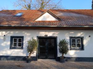 a white house with a black door and two trees at Press4Living Cottage near Vienna in Ebenthal