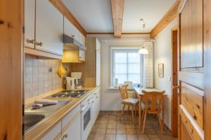 a kitchen with white cabinets and a table with chairs at Direkt am Deich - Ferienwohnung Föhr im Gästehaus Am Badedeich in Dagebüll