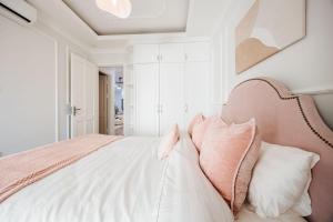 a white bedroom with a large bed with pillows at Soleil Residence Westlake Hanoi in Hanoi