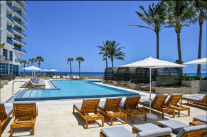 a pool at the beach with chairs and umbrellas at 2BR 2BA condo with ocean views in Luxury Resort Amrit in Riviera Beach
