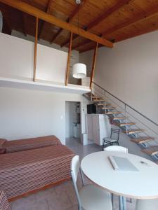 a room with a bed and a table and a staircase at Costa del Faro Apart Hotel in Balneario El Condor