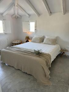 a white bedroom with a large bed with a blanket at Vista Las Colinas in Córdoba
