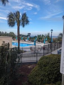 a fence in front of a pool with a palm tree at Seascape Retreat in Tybee Island