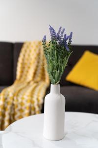 a white vase with purple flowers on a table at Open Mind Property - 2 Beds & FREE Parking in Brockhurst