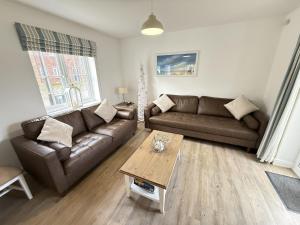 a living room with a couch and a coffee table at New England Cottage - Part of the The Bay Filey Holiday Village with pool, gym and direct beach access, pub, restaurant, tennis and meadows walks in Filey