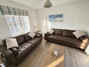 a living room with a brown couch and a table at New England Cottage - Part of the The Bay Filey Holiday Village with pool, gym and direct beach access, pub, restaurant, tennis and meadows walks in Filey