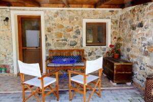 a table and chairs on a patio with a stone wall at Siena Cottage in Makri