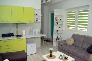 a living room with a couch and a kitchen with green cabinets at Simona Apartman in Bitola
