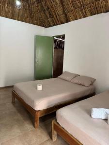 two beds in a room with a cup on top at Cabañas Camping Ria Celestun in Celestún +19 photos