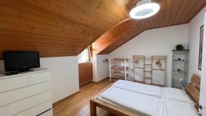 a bedroom with a bed and a tv and a wooden ceiling at NEW Suite mar e monti in Appiano sulla Strada del Vino