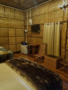 a room with a bed and a table and a television at Alohi The Cottage Homestay in Tezpur