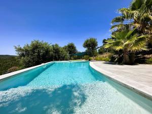 a swimming pool with blue water and palm trees at Villa Azur climatisée pour 6 personnes avec piscine et belle vue mer à La Londe les Maures in La Londe-les-Maures